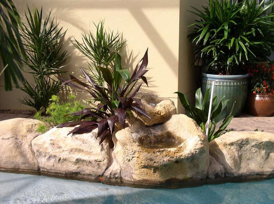 Townhouse landscape with rocks and blue water and flowers